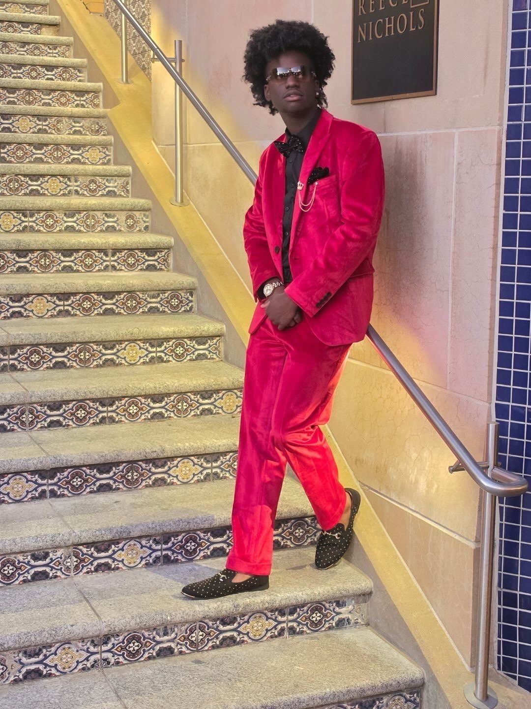 Young man in a red velvet suit posing on a tiled staircase