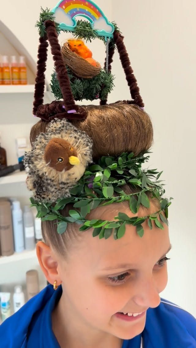Girl with elaborate nature-themed hair sculpture featuring a bird, nest, and rainbow.