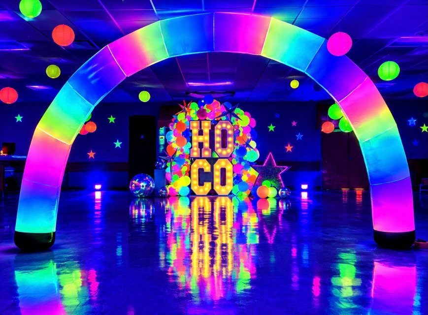 Rainbow glowing archway and neon HO CO sign in a dark dance hall
