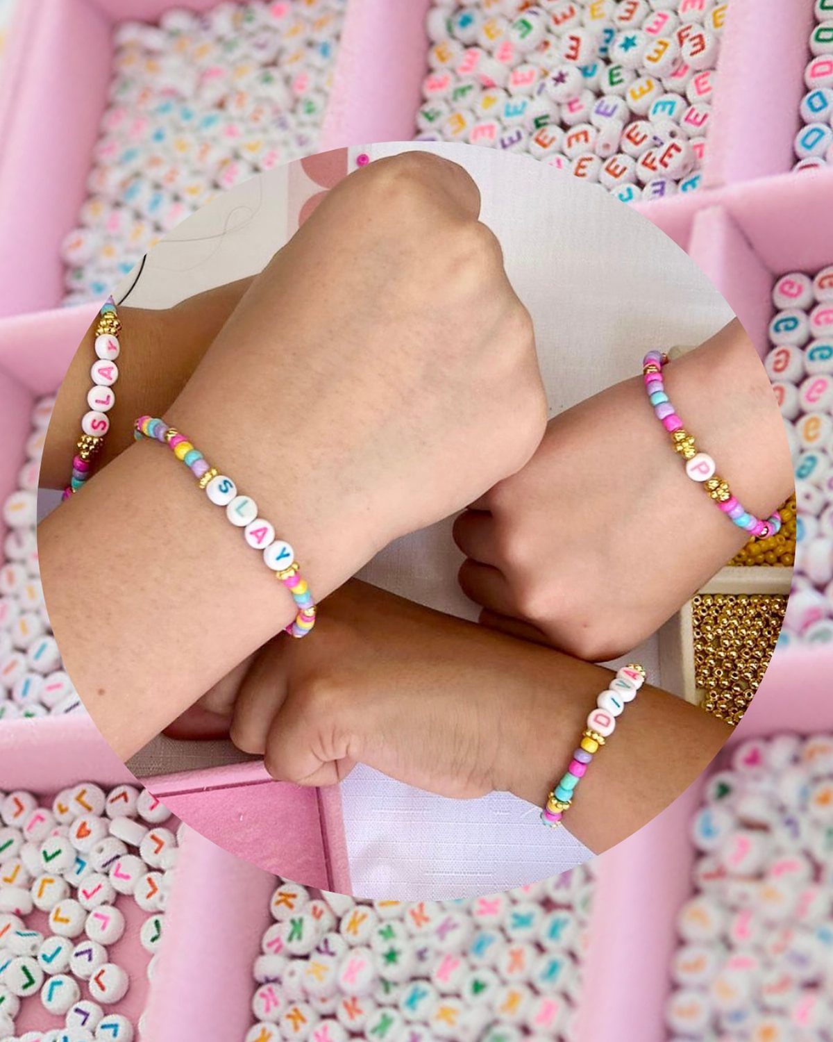 Children's wrists wearing colorful beaded friendship bracelets over a tray of alphabet beads.