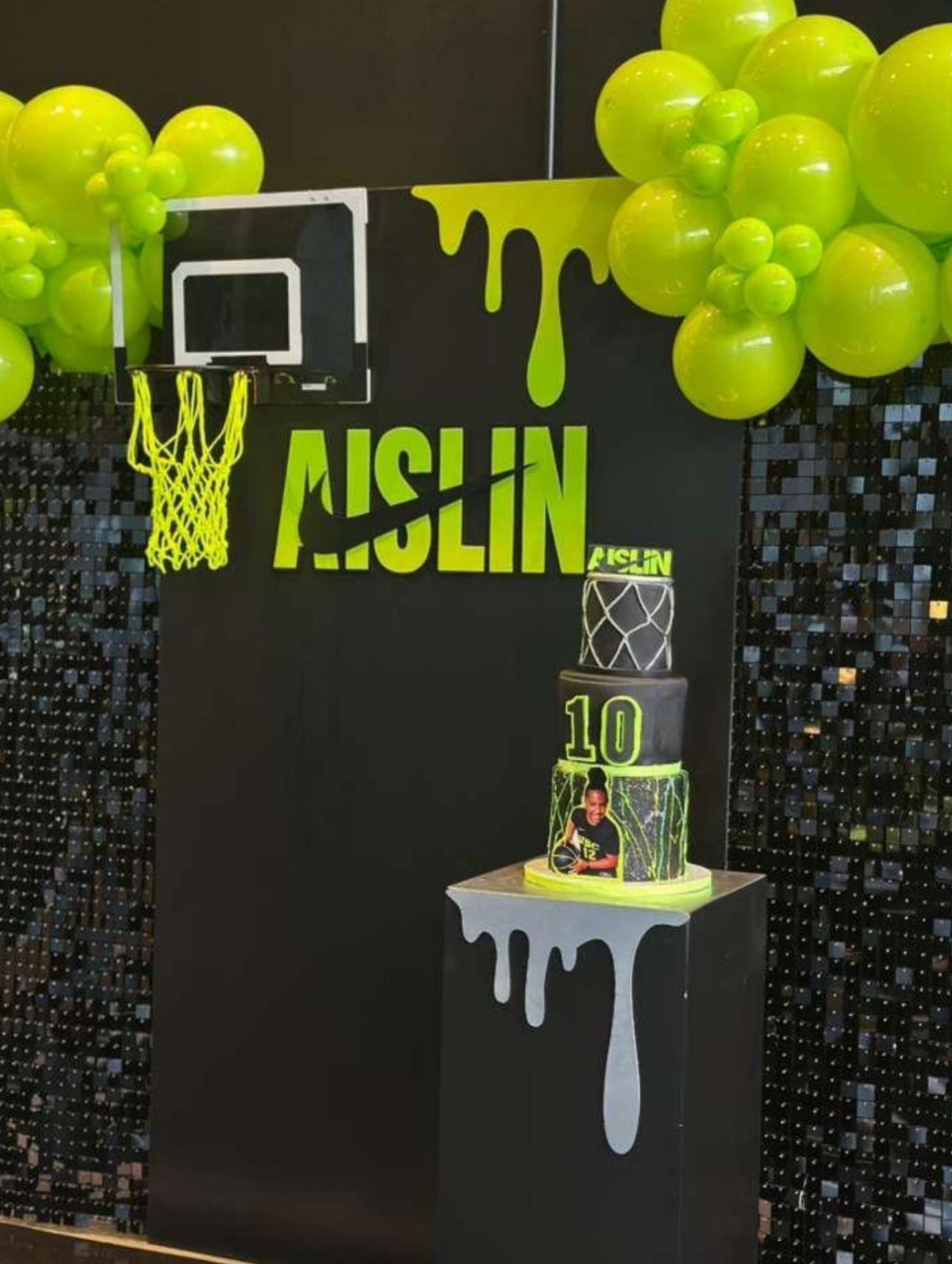 Basketball themed party decorations with neon green balloons and a tiered cake.