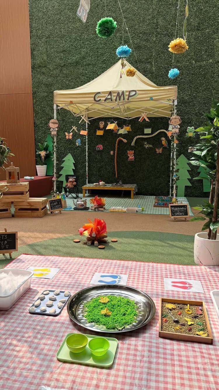 Camping themed classroom setup with a small tent, fake campfire, and sensory bins.