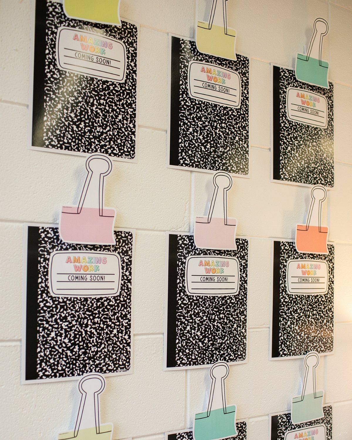 Composition notebook themed wall decor with colorful clips and student work labels.