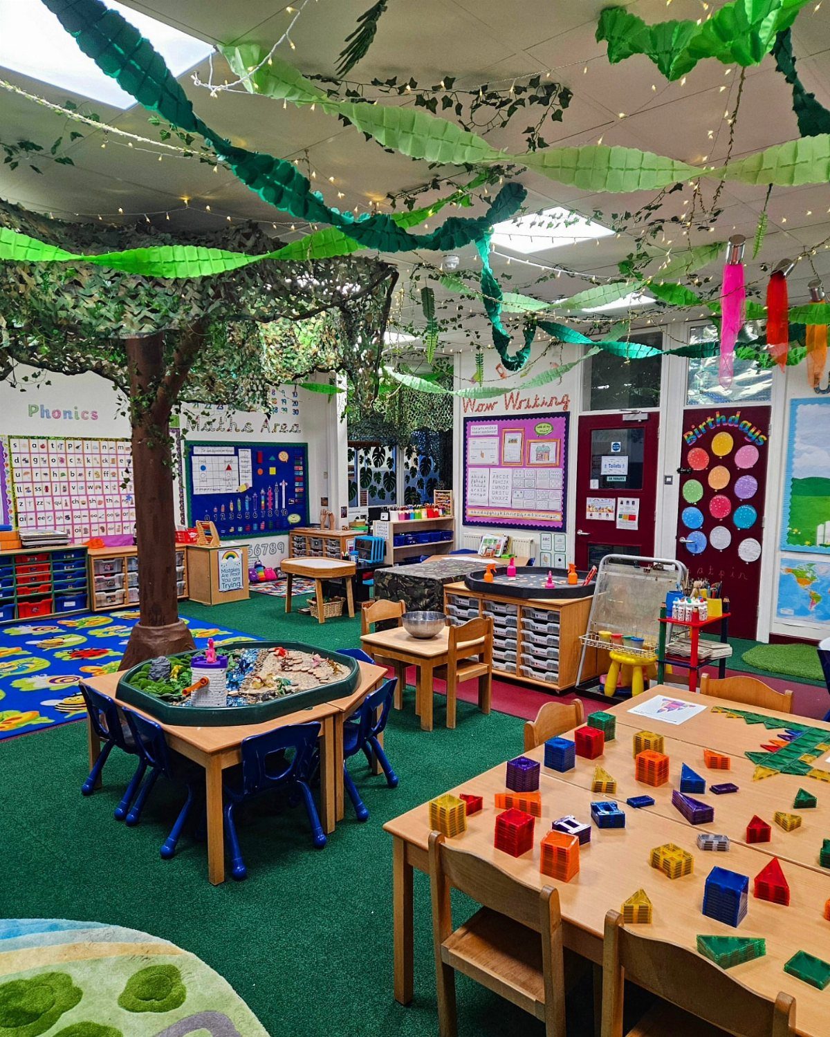 Kindergarten classroom decorated with a nature theme featuring a fake tree and vines.