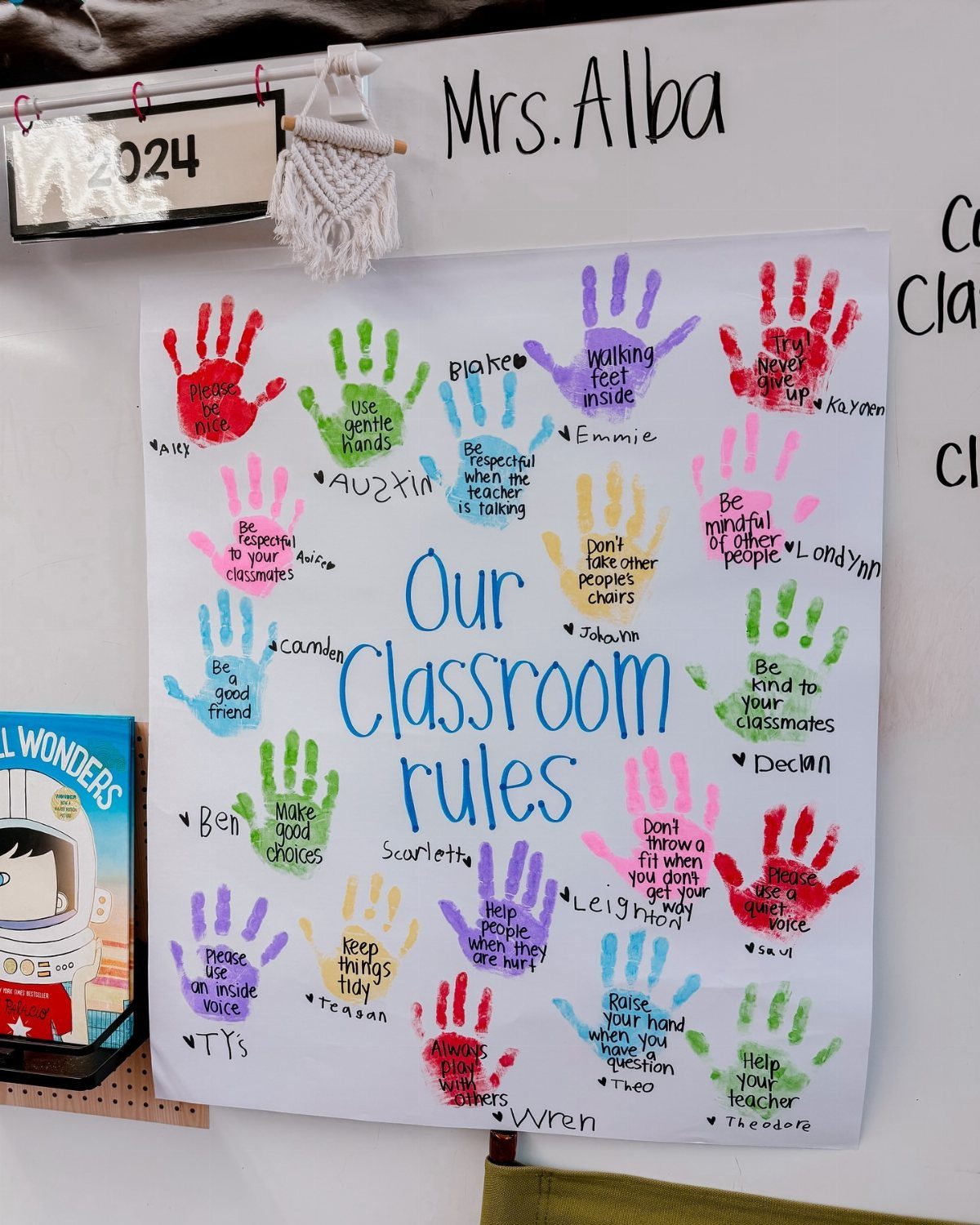 Classroom rules poster with colorful student handprints and handwritten behavioral guidelines.
