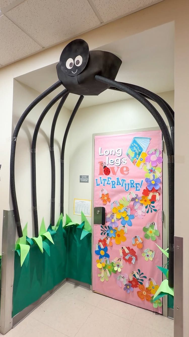 Black spider arch over a pink door decorated with colorful paper flowers.