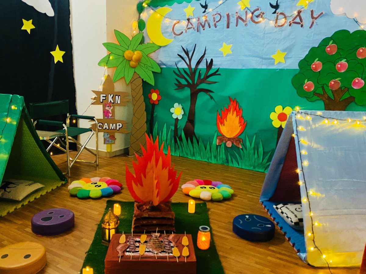 Camping themed classroom setup with tents, a fake campfire, and nature backdrop.