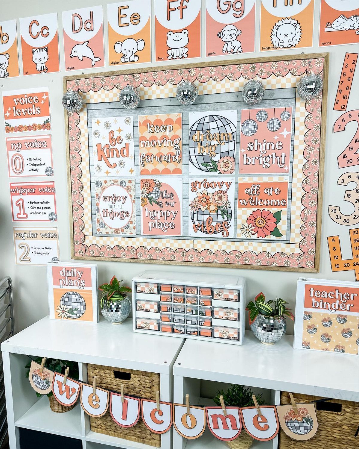Classroom bulletin board and shelving decorated with disco balls and orange retro accents.