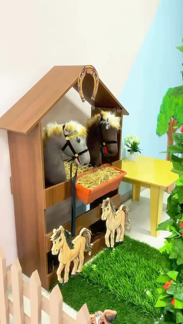 Horse-themed classroom play area with wooden stable, plush horses, and artificial grass.