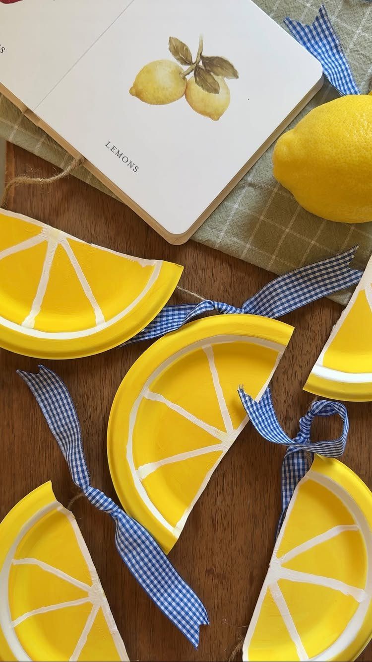 Yellow paper plate lemon slices with blue checkered ribbons on a wooden table.
