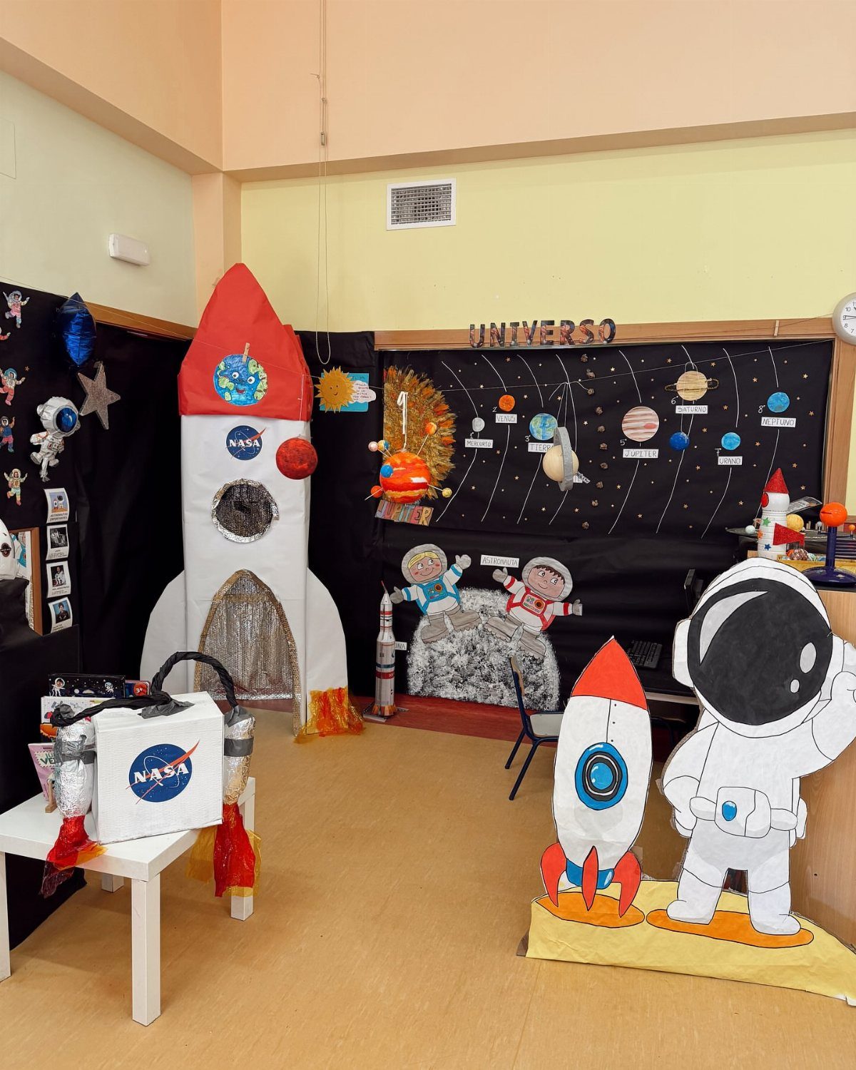 Space themed classroom corner with a large rocket ship, astronaut cutout, and planet display.