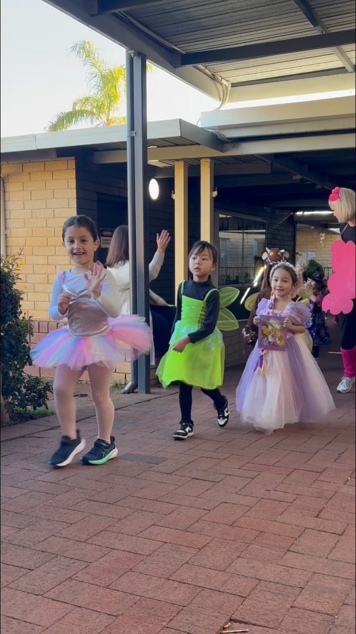 Young girls in colorful fairy and princess costumes walking in a Halloween parade.