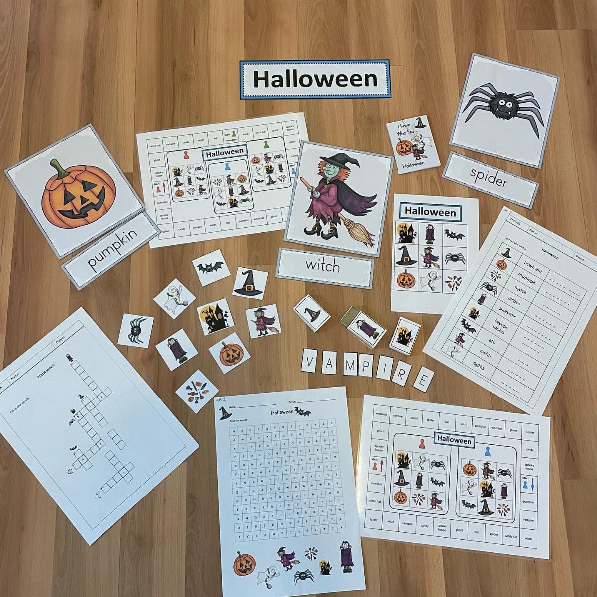 Halloween bingo cards and activity sheets spread across a light brown wooden floor.