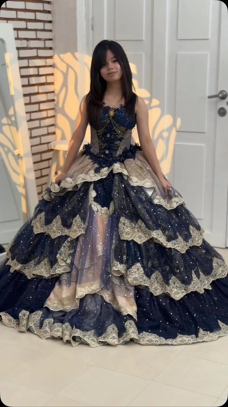 Young woman in a voluminous dark blue ballgown with gold lace trim.