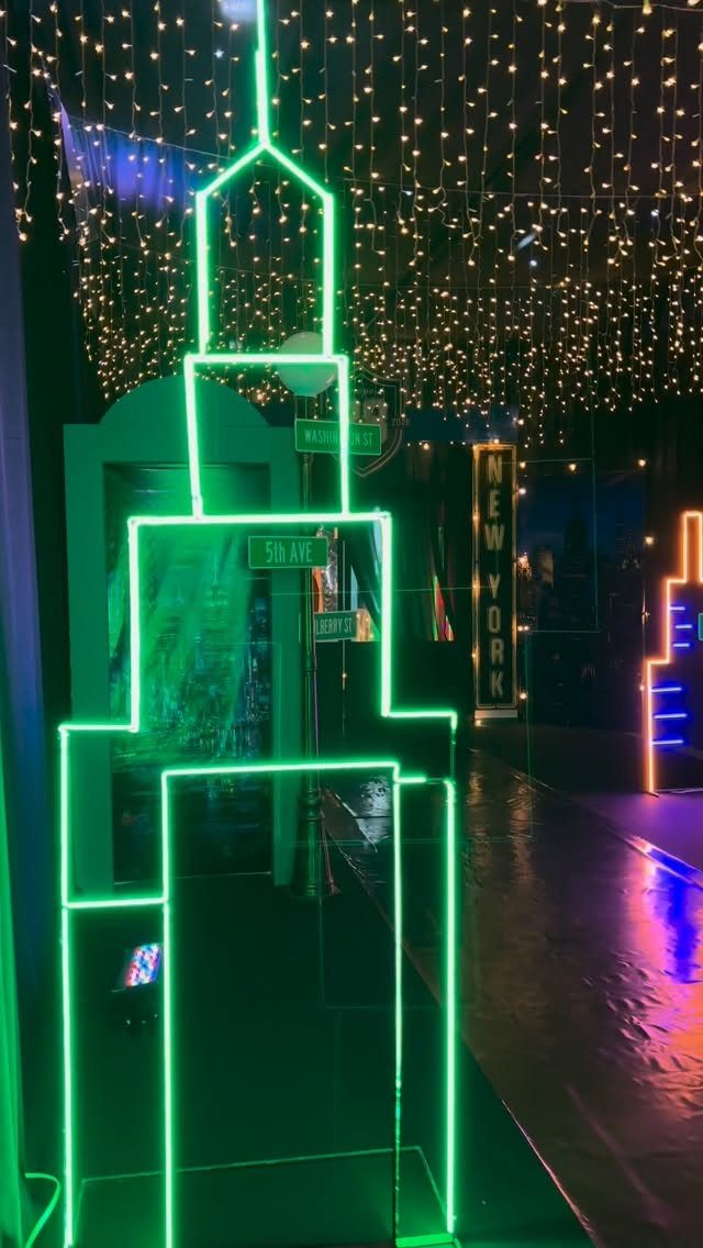 Green neon skyline sculpture with hanging fairy lights and New York signage.