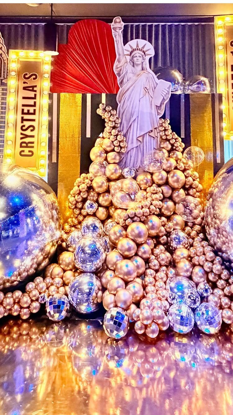 Statue of Liberty figure atop gold and silver disco balls with marquee lighting