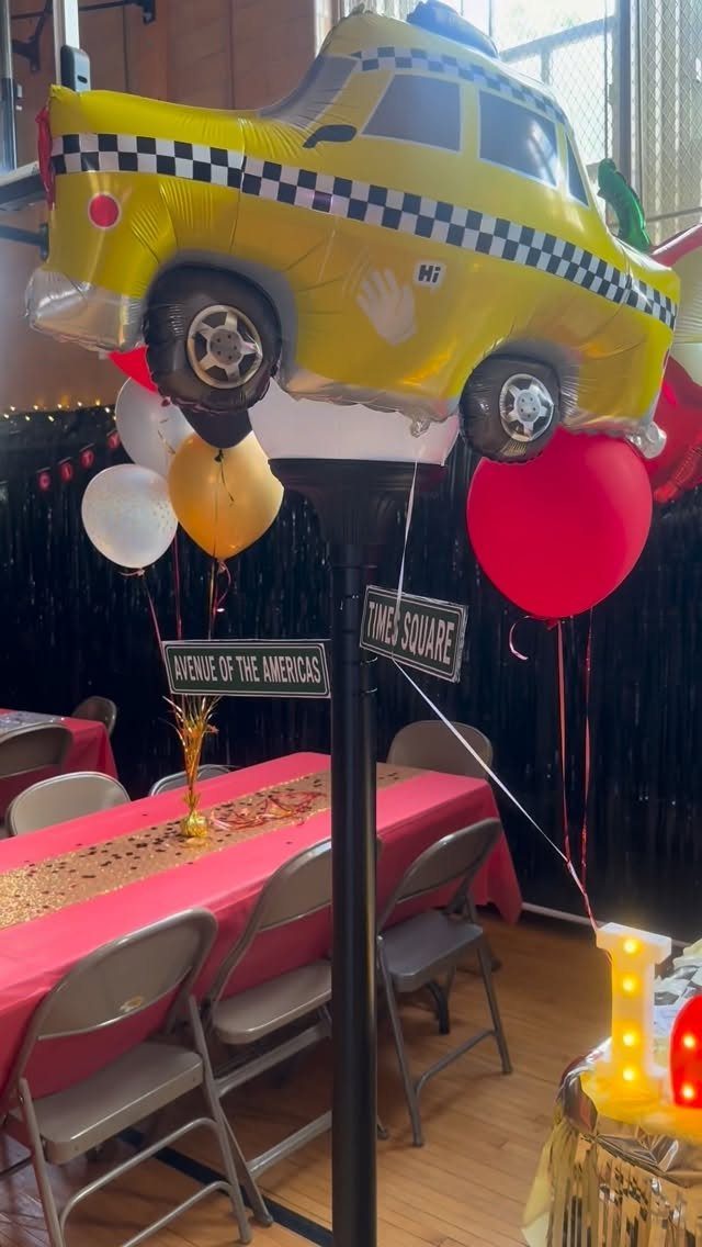 Yellow taxi balloon decoration with New York street signs for a themed event.