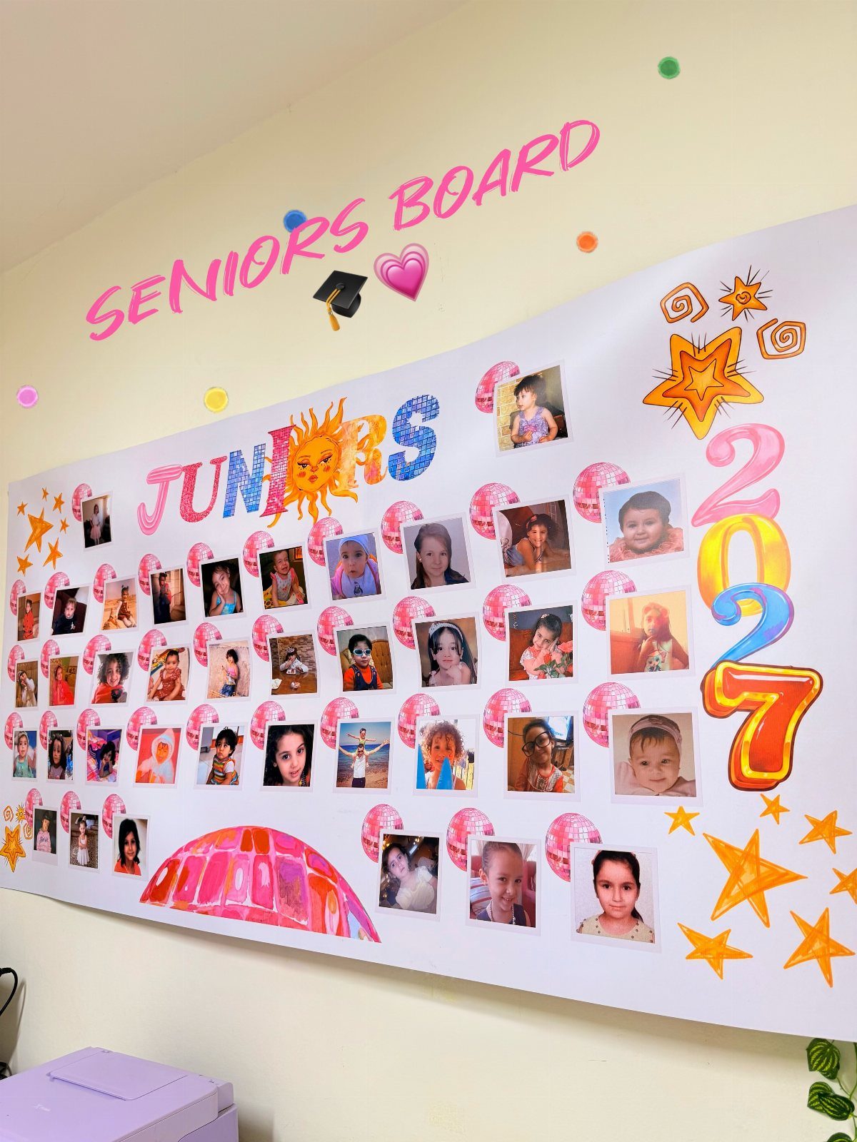 Wall display board with children's photos, colorful stars, and the text Seniors Board.