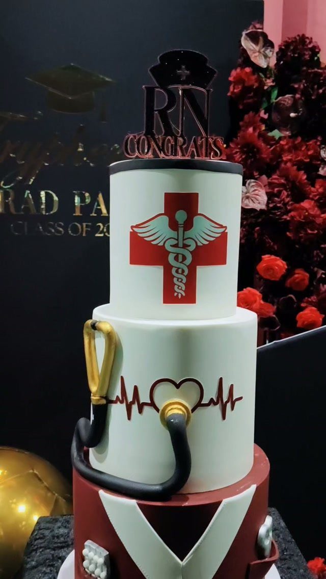 Three-tier nursing graduation cake with a caduceus, stethoscope, and EKG heart line.