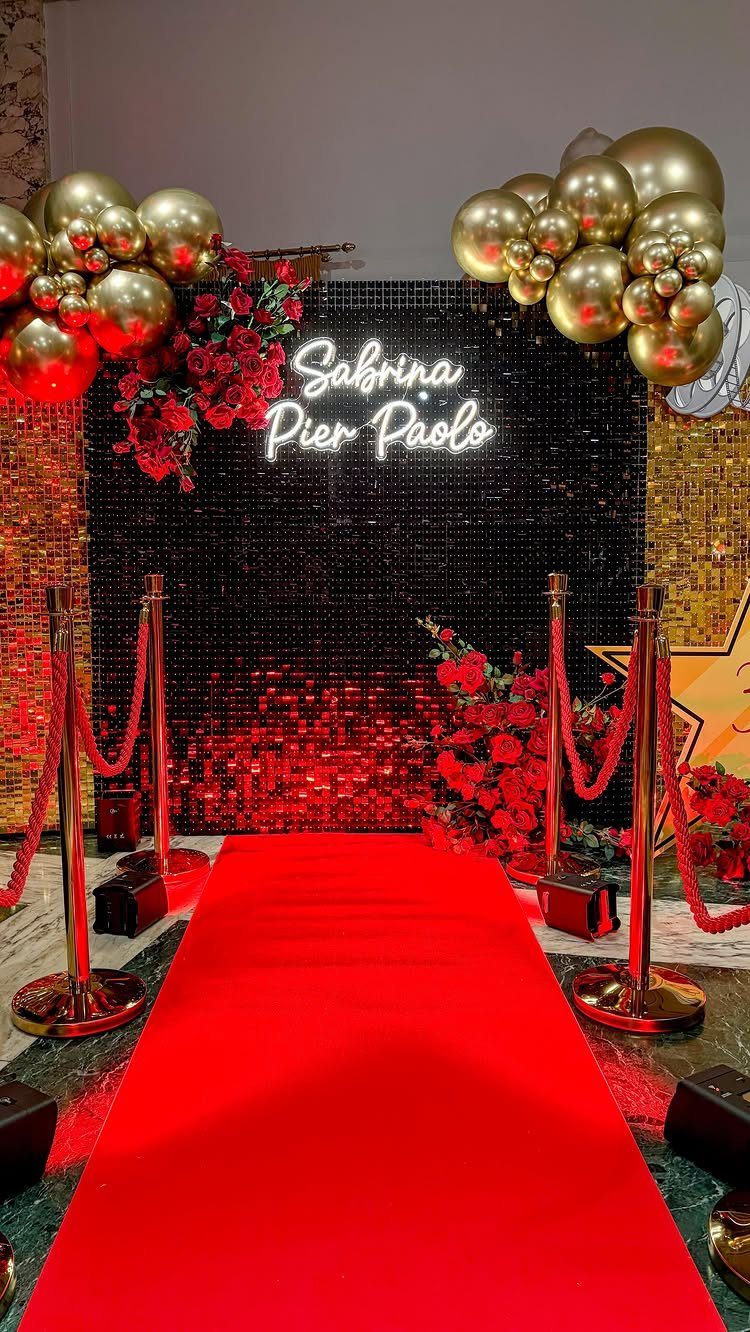 Red carpet entrance with gold balloons and a black sequin backdrop for an event