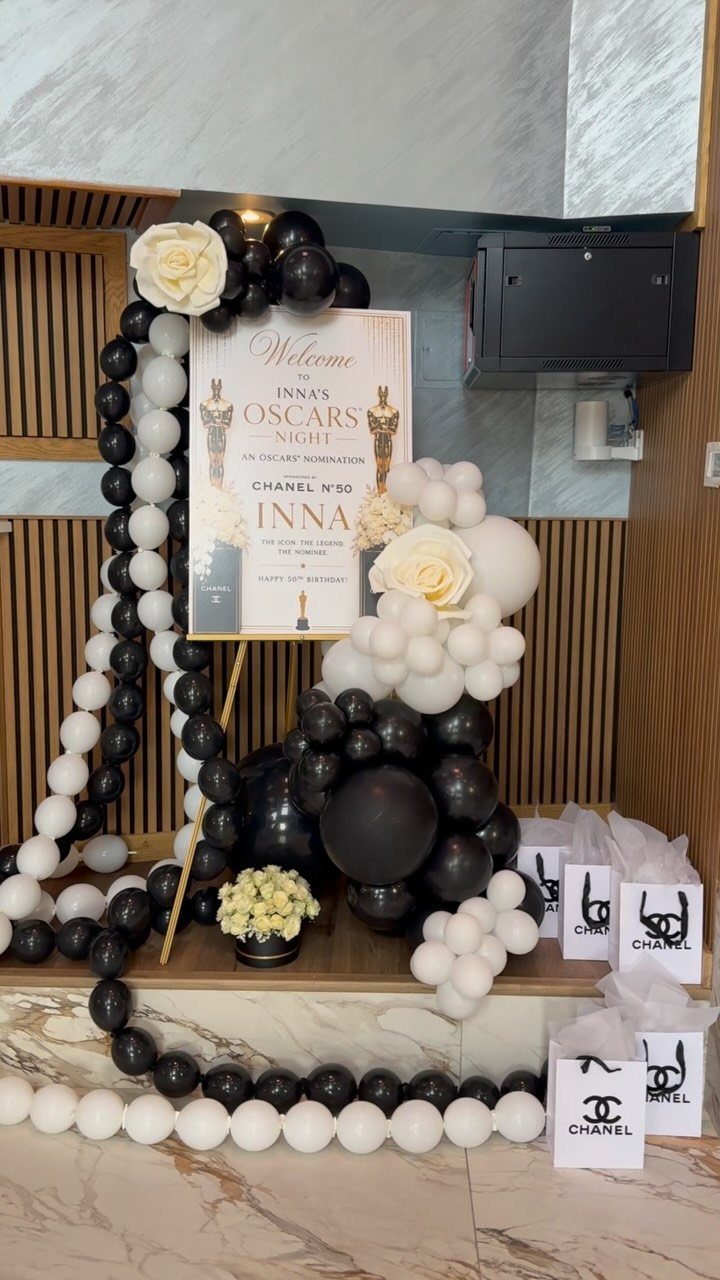 Black and white balloon garlands framing an Oscars Night welcome sign with roses.
