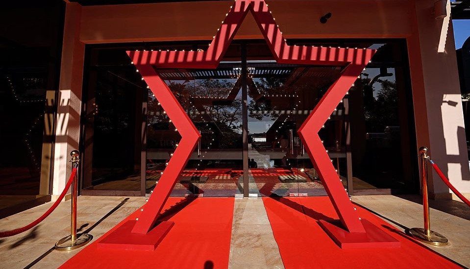 Red star-shaped archway with lights over a red carpet with gold stanchions.