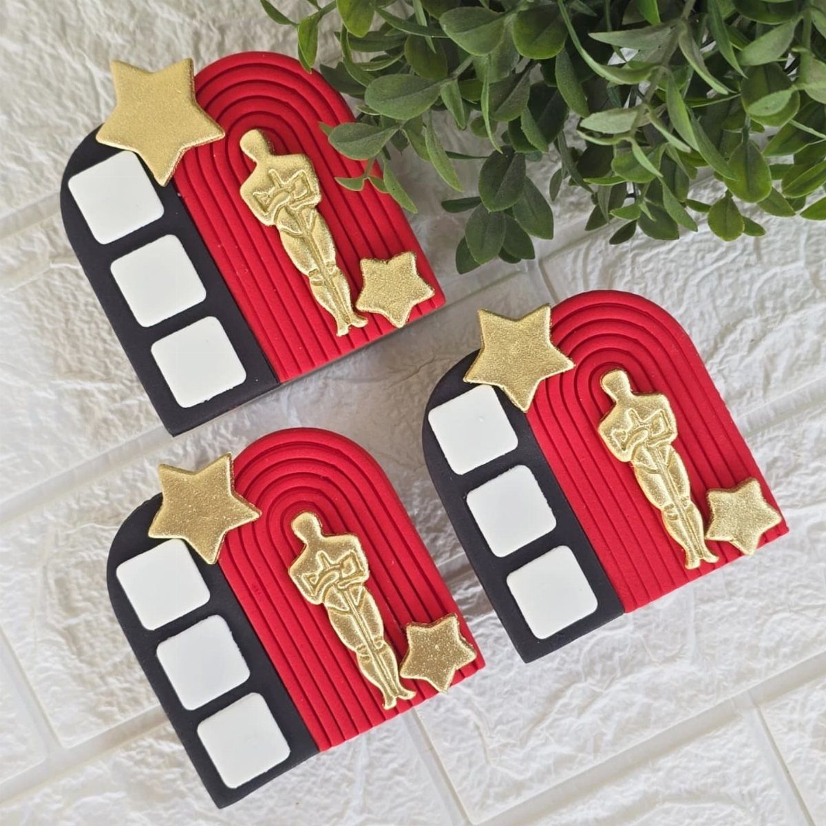 Movie clapboard cookies with red carpets and gold award statues on white brick.