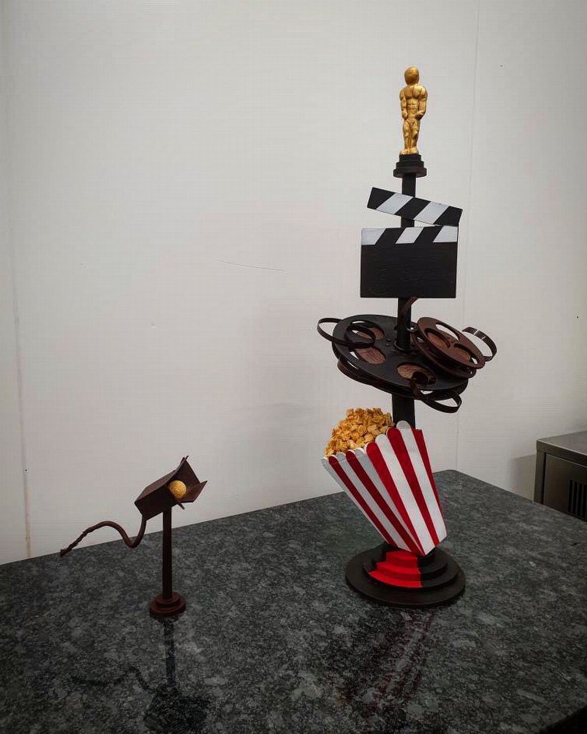 Movie-themed centerpiece with gold trophy, clapperboard, film reels, and popcorn bucket.