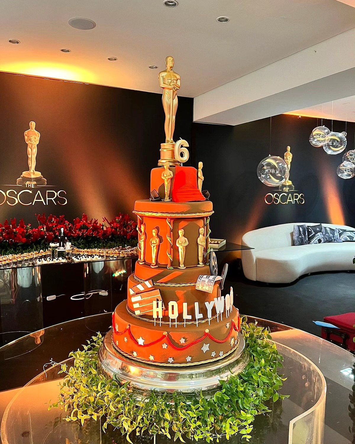 Oscar themed cake with gold trophies in a decorated party room