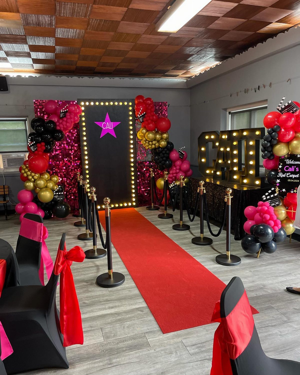 Red carpet runner leading to a star-themed photo backdrop with balloons and stanchions.