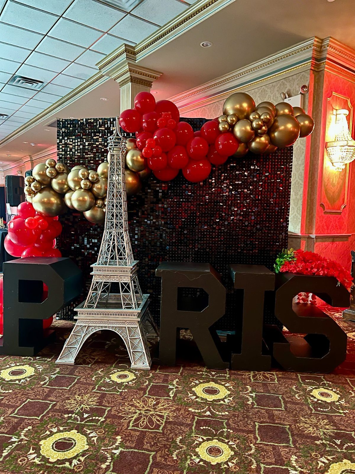 Silver Eiffel Tower model and black PARIS letters with red and gold balloons.