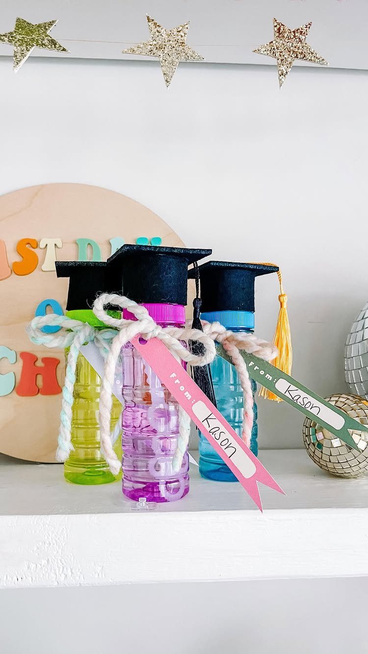 Graduation themed party favors featuring small colorful bottles with miniature black mortarboards.