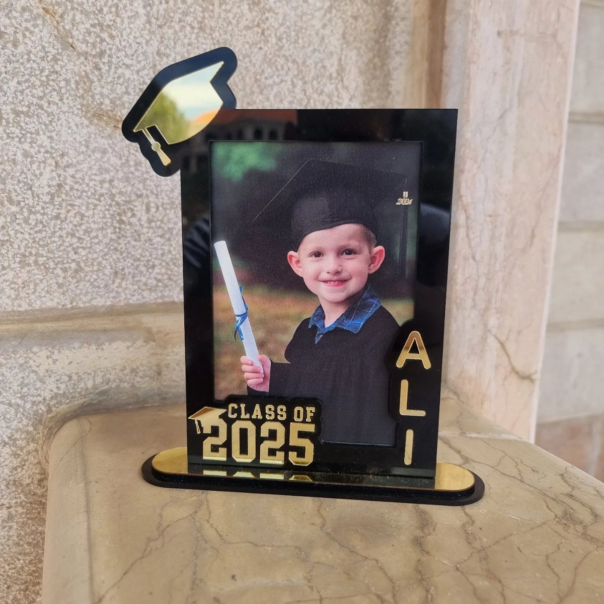 Personalized black acrylic graduation photo frame with gold accents and a child's portrait.