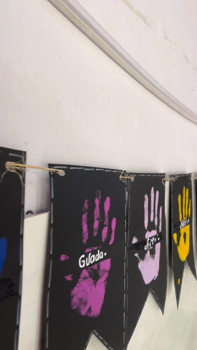 Black bunting flags with colorful painted handprints hanging on a white wall