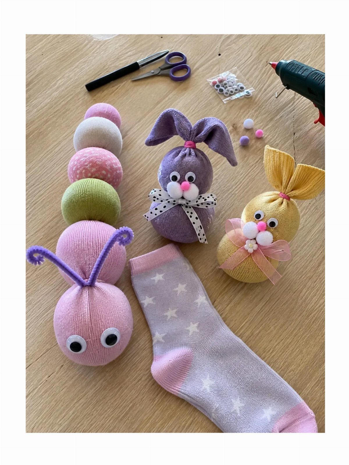 Handmade sock puppets and craft tools arranged on a light wooden surface.