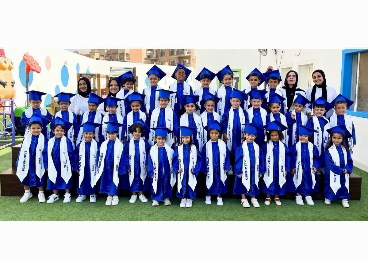 Preschool students and teachers posing in blue graduation gowns and caps for a photo.