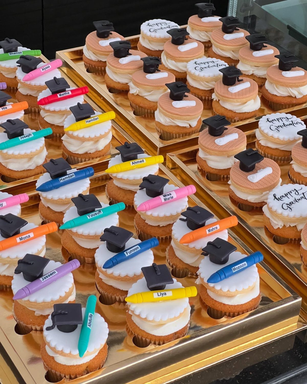 Graduation cupcakes topped with miniature black caps and colorful personalized edible markers.