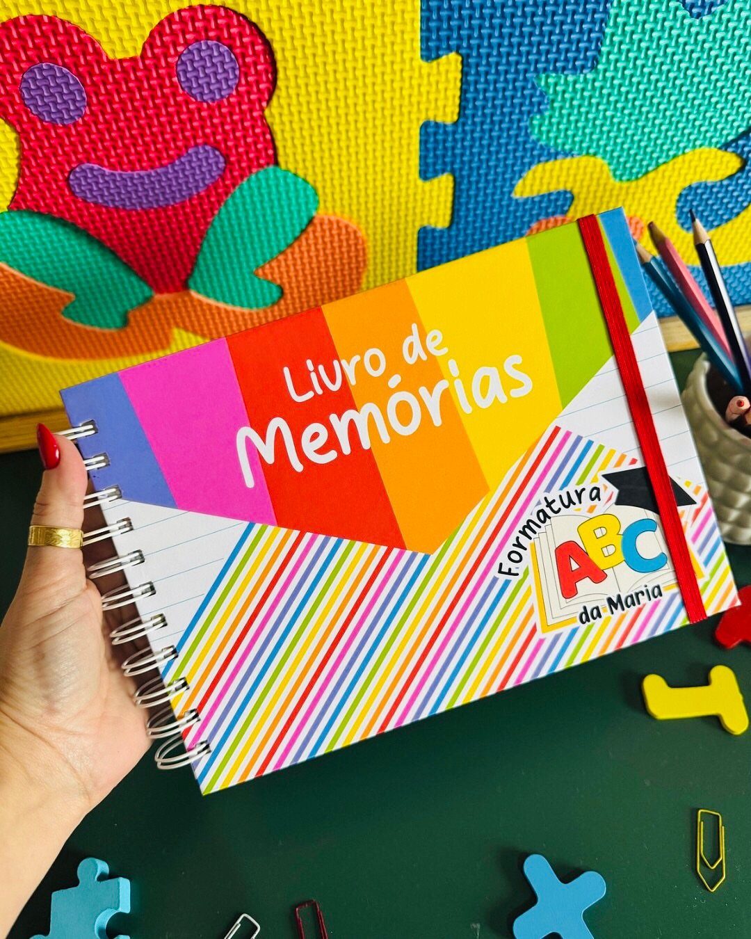 Colorful spiral memory book held by a hand over bright puzzle mats.
