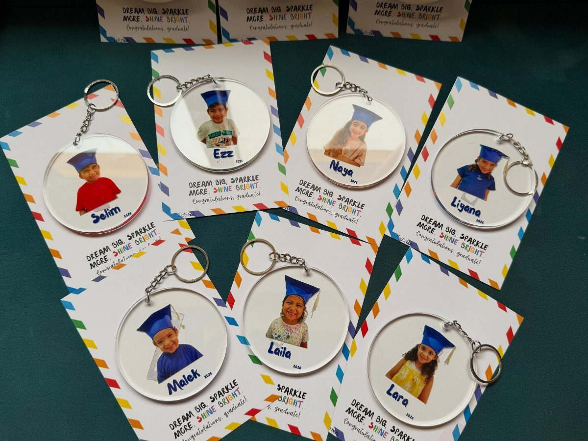 Graduation keychains with photos of children in blue caps and gowns on cards.