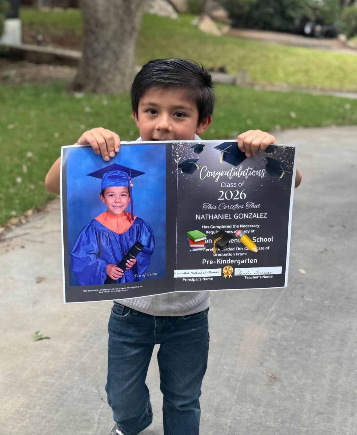 Young boy holding a large preschool graduation certificate with his photo on it.
