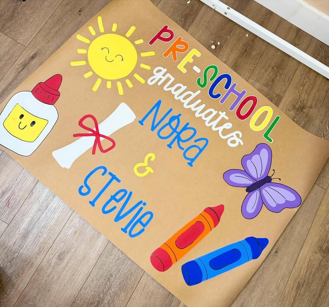 Brown paper banner with colorful preschool graduation text and school-themed illustrations.