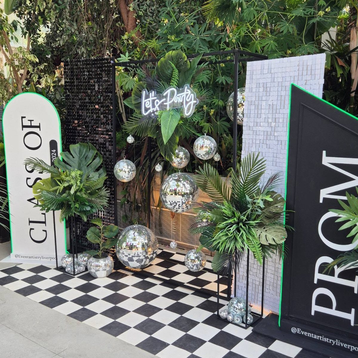 Checkered floor and neon sign with disco balls and tropical plants for prom.