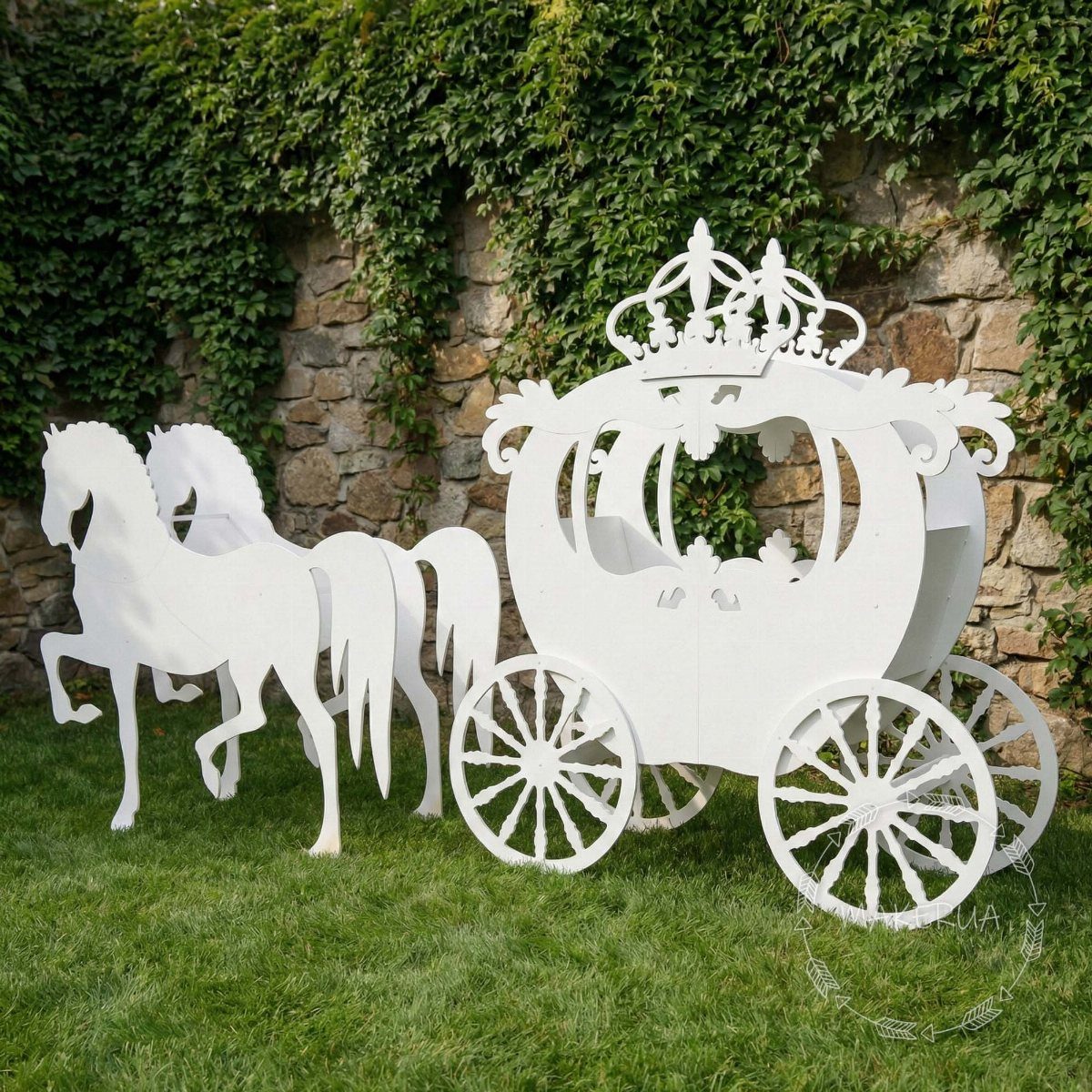 White wooden carriage and horse cutouts on grass against an ivy stone wall