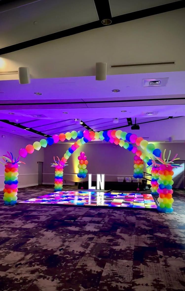 Rainbow balloon arch and pillars surrounding a glowing multi-colored LED dance floor.