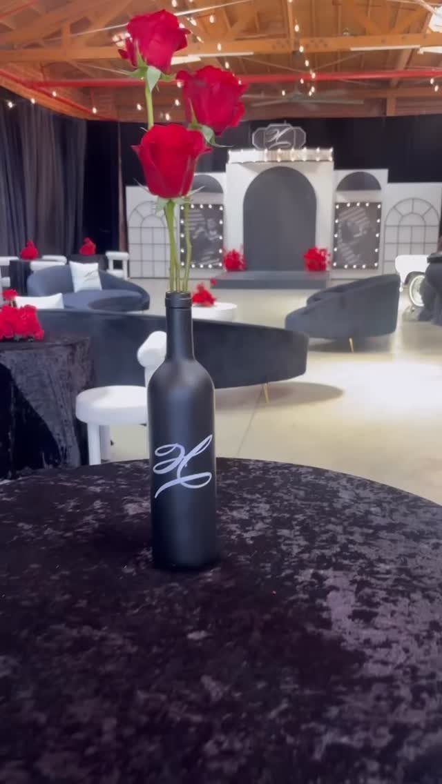 Red roses in a black bottle on a velvet table in a glamorous lounge