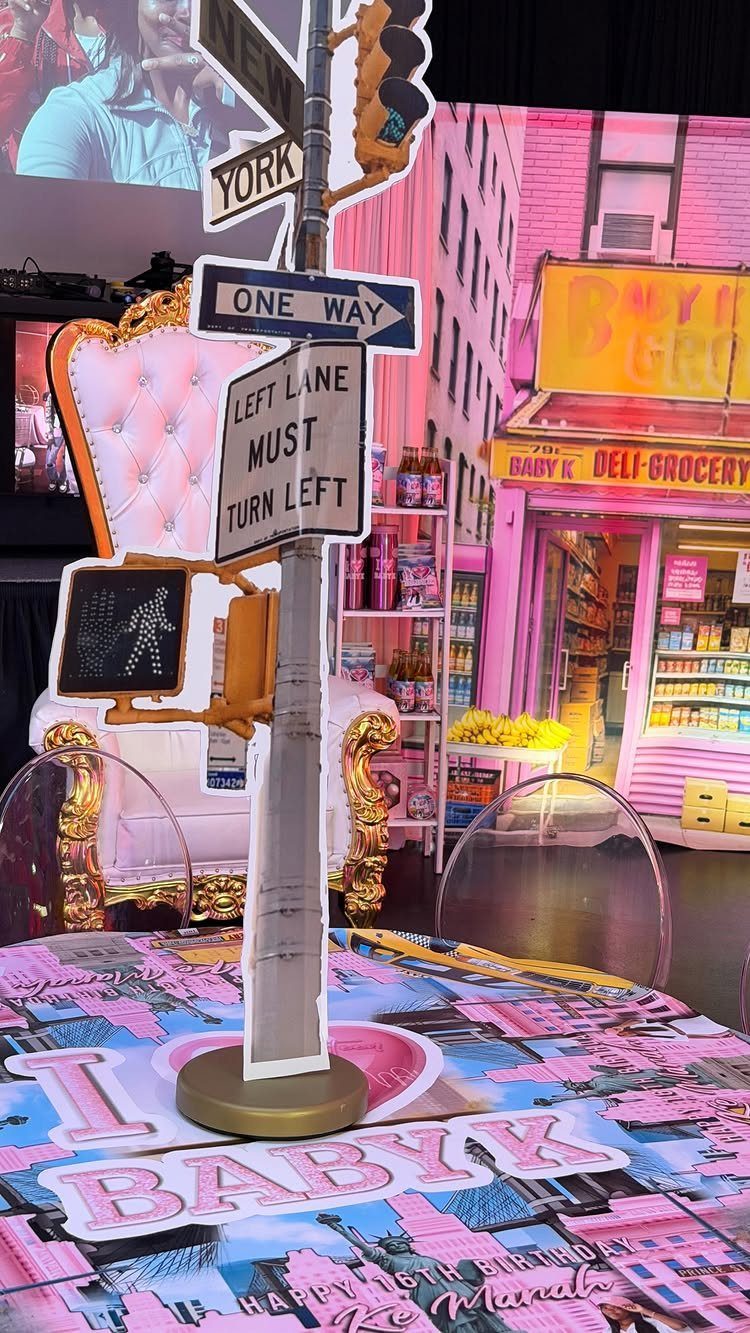 New York City street sign prop in front of a pink deli backdrop.