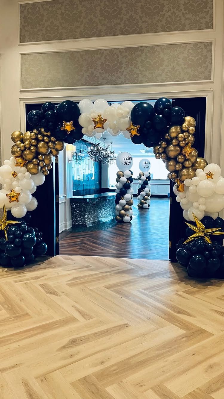 Balloon arch in black, gold, and white framing an event entrance.