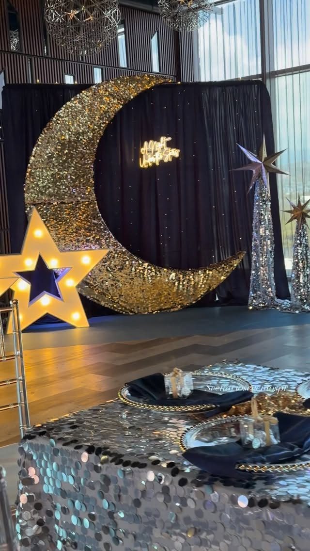 Gold sequined crescent moon and glowing star backdrop with silver sequined table settings.