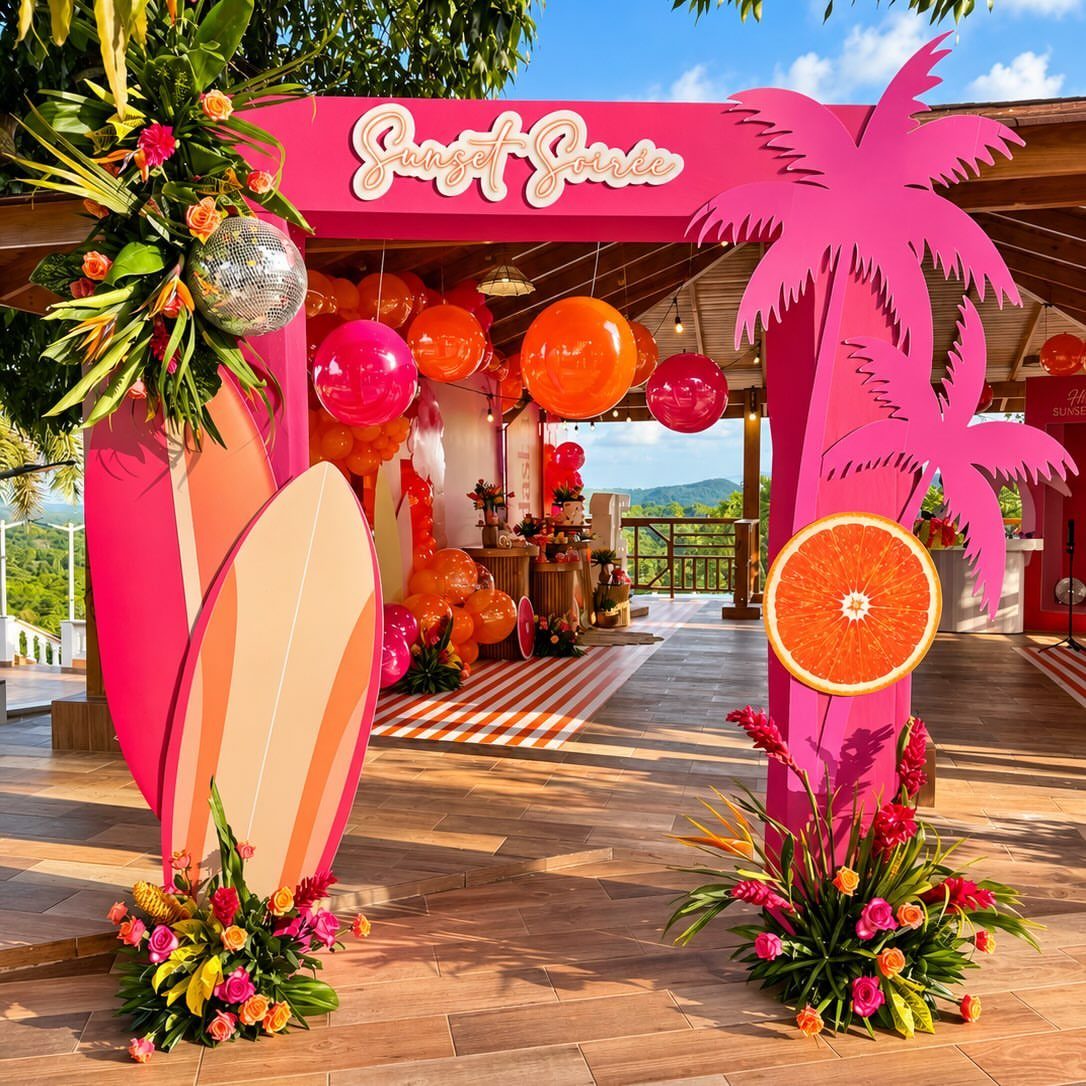 Tropical entrance decor with pink palm trees, surfboards, balloons, and colorful flowers.