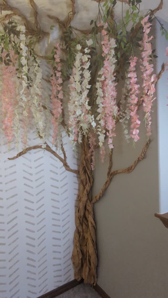 Artificial decorative tree with hanging pink and white flowers against a patterned wall